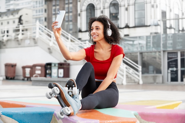 Bezpłatne zdjęcie kobieta z wrotkami robi selfie na zewnątrz