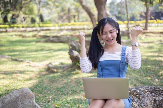 kobieta za pomocą laptopa, podnosząc ramiona z wyglądem sukcesu.