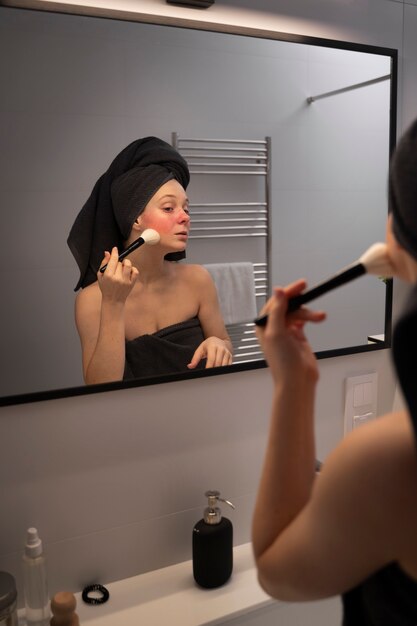 Kobieta zajmująca się trądzikiem różowatym nakładająca makijaż pędzlem