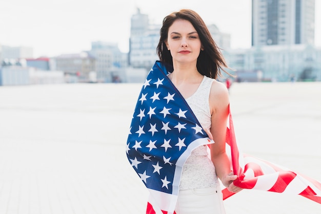 Bezpłatne zdjęcie kobieta zawinięte w amerykańską flagę i patrząc na kamery