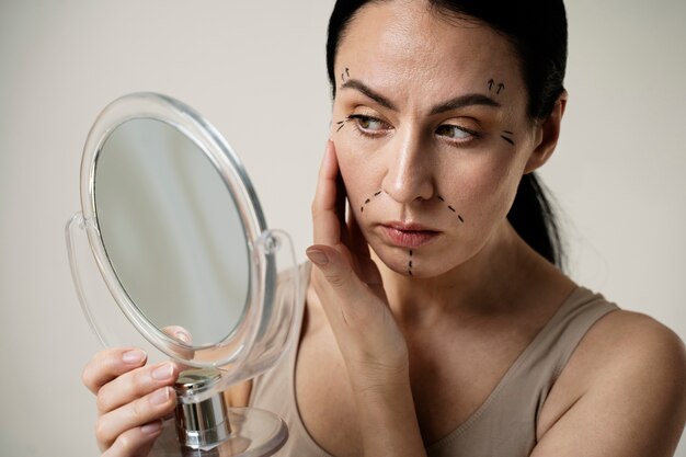Kobieta ze śladami markera na twarzy patrząca w lustro