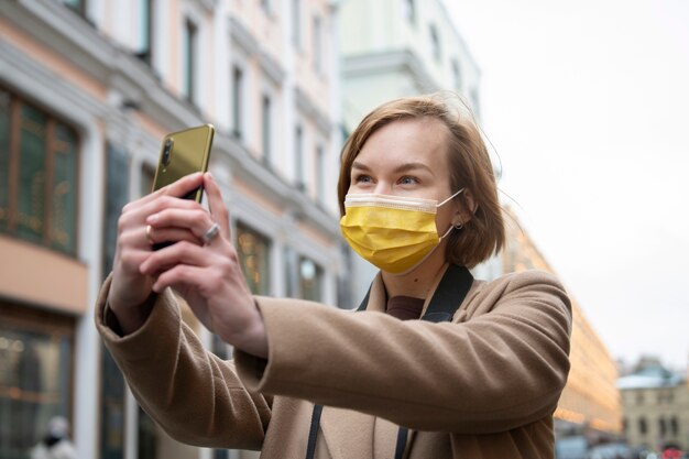 Kobieta ze średnim strzałem w masce robi selfie