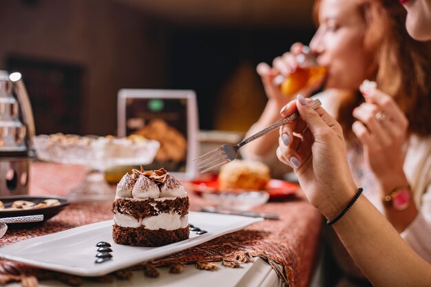 Kobieta zje porcjonowane warstwowe ciasto kakaowe z białą śmietaną i kawałkami czekolady