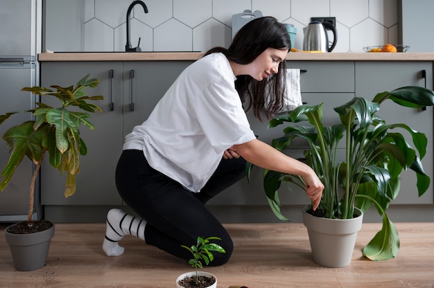 Kobieta zmienia doniczki ze swoimi roślinami w domu podczas kwarantanny