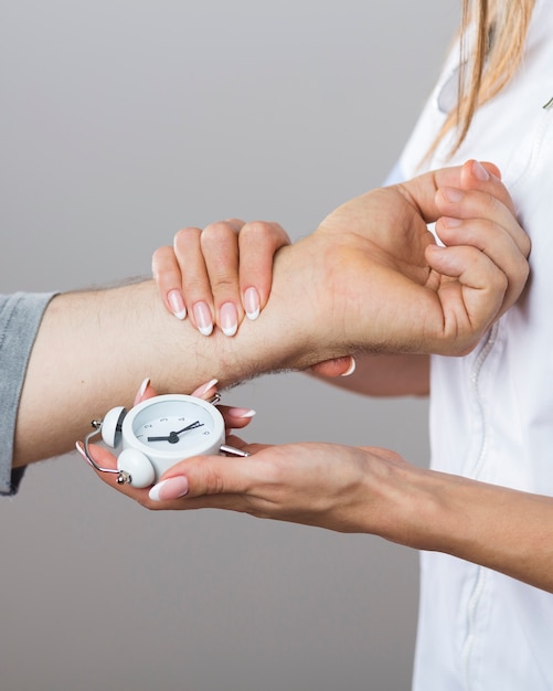 Bezpłatne zdjęcie kobiety doktorski mienie zegar i cierpliwa ręka