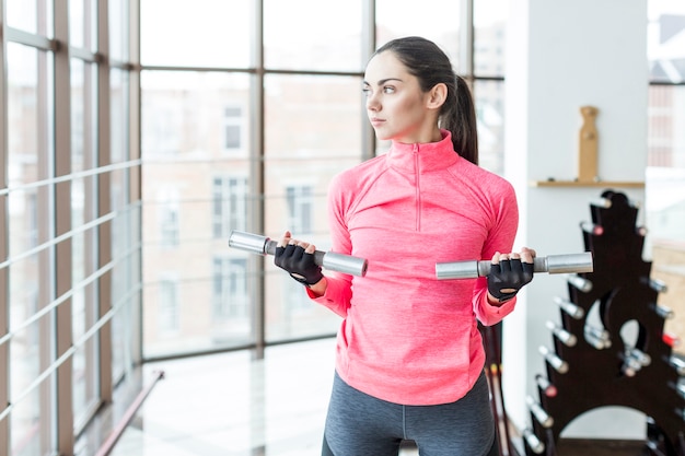 Bezpłatne zdjęcie kobiety mienia dumbbells w gym