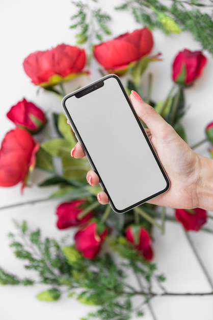 Kobiety mienia smartphone z pustym ekranem nad róże