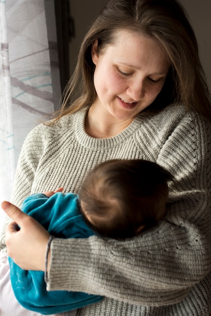 Bezpłatne zdjęcie kobiety mienia sypialny dziecko w rękach