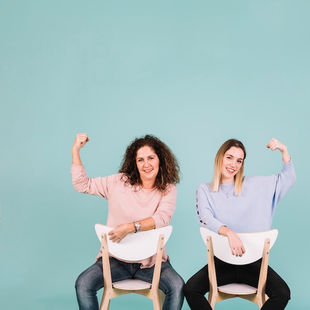 Kobiety na krzesłach pokazujący gest mocy
