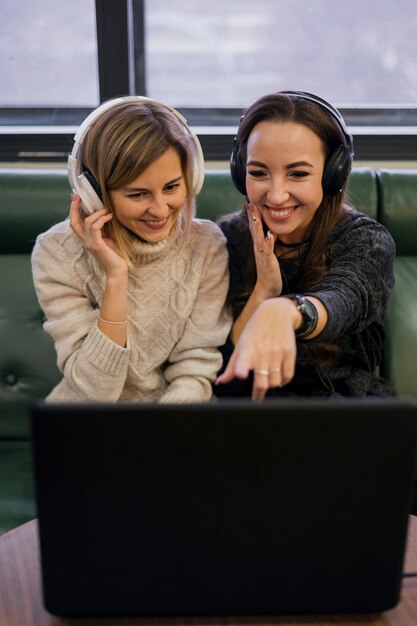 Kobiety noszące słuchawki patrząc na laptopa