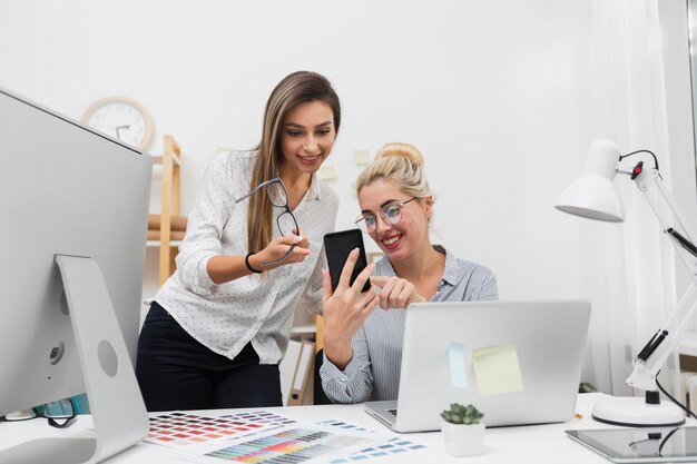 Kobiety patrzeje na telefonie przy biurem