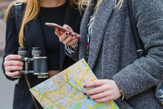 Kobiety przeglądające smartfię z mapą