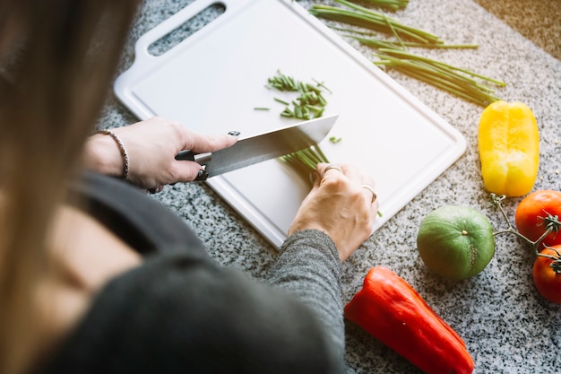 Kobiety ręki rozcięcia scallion na ciapanie desce w kuchni