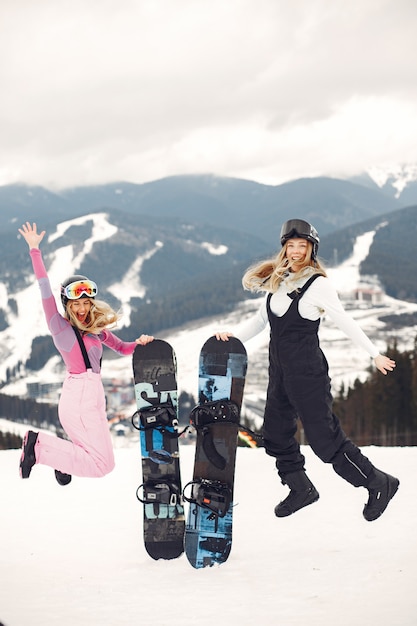 Kobiety w kombinezonach snowboardowych. Sportsmenki na górze ze snowboardem w rękach na horyzoncie. Koncepcja sportu