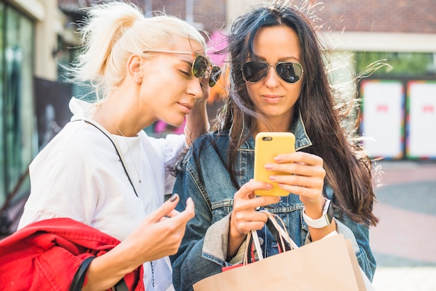 Kobiety w okulary przeciwsłoneczne za pomocą smartfona