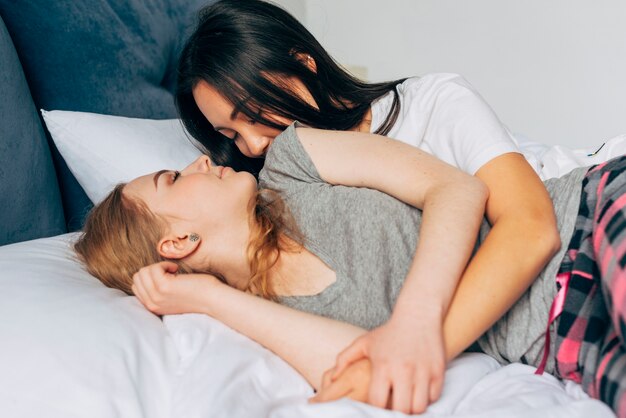 Kobiety w piżamie przebywające w łóżku i przytulane razem