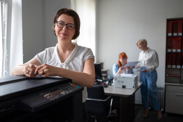 Bezpłatne zdjęcie kobiety w pracy w biurze przy użyciu drukarki