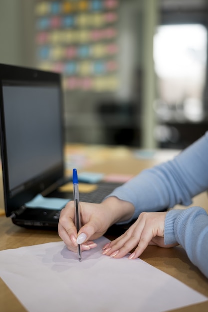 Bezpłatne zdjęcie kobiety writing na papierze przy biurem