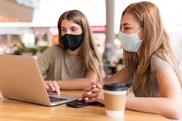 Bezpłatne zdjęcie kobiety z maską pracuje na laptopie