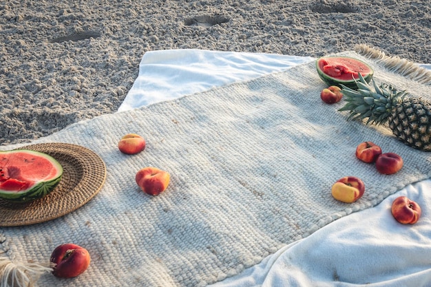 Bezpłatne zdjęcie koc z owocami na koncepcji pikniku na piaszczystej plaży