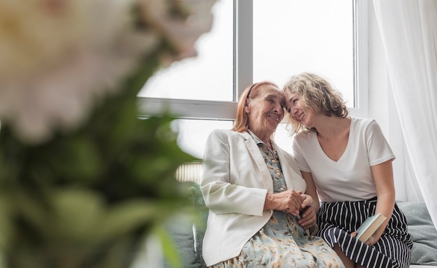 Bezpłatne zdjęcie kochająca kobieta z jej babci siedzi na kanapie w domu