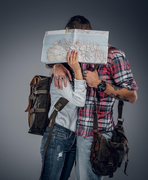 Bezpłatne zdjęcie kochająca para gotowa do podróży z plecakami i mapą. mężczyzna całuje kobietę.