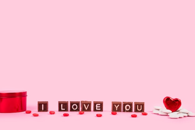 Kocham Cię napis na kawałkach czekolady pomiędzy pudełkiem i ornamentem serca