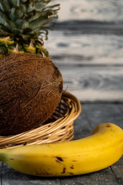 Kokosowy ananas i banan w łozinowym koszu na stole