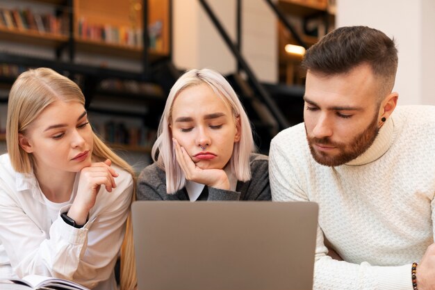 Koledzy rozmawiają i uczą się w bibliotece przy użyciu laptopa