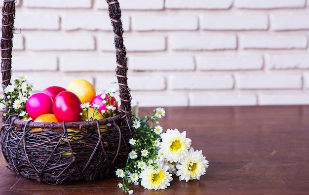 Bezpłatne zdjęcie kolorowe jaja wielkanocne w koszyku brązowe z kwiatem