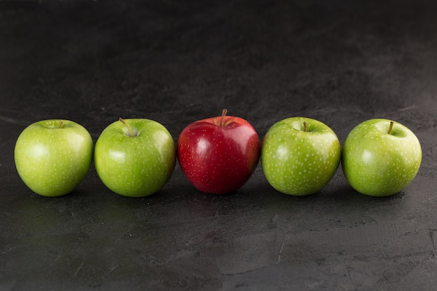 Kolorowe owoce jeden czerwony i cztery zielone, łagodne, świeże, dojrzałe jabłka na szarym biurku