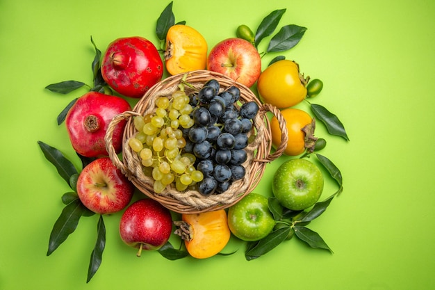 Bezpłatne zdjęcie kolorowe owoce kosz winogron granat jabłka persimmons i liście