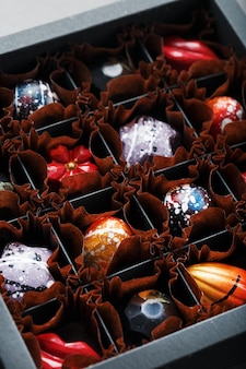 Kolorowe ręcznie robione czekoladki w pudełku na ciemnym tle