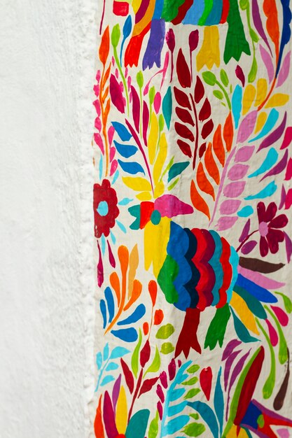 Kolorowy ptak i liście na białej ścianie