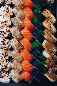 Kolorowy pyszny zestaw sushi leżący na talerzu zawierający różne składniki rybny kawior ryż ogórek łosoś sos sojowy wasabi sezam ciekawa prezentacja