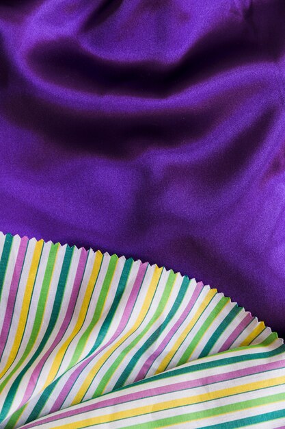 Kolorowych lampasów deseniowy stołowy płótno na gładkiej purpurowej tkaninie