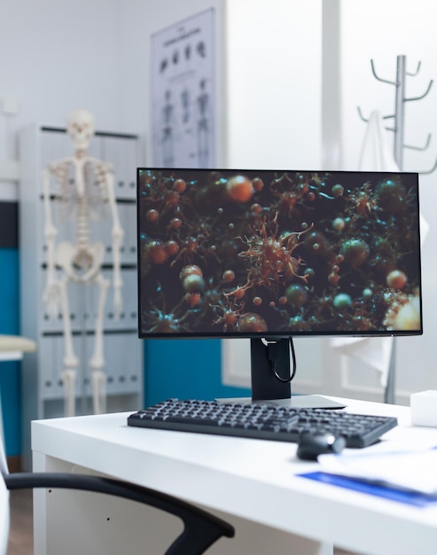 Komputer z ilustracją komórki wirusa na ekranie gotowy do konsultacji z pacjentem w pustym biurze. Sala szpitalna wyposażona w profesjonalne narzędzia medyczne. Usługi wsparcia opieki zdrowotnej