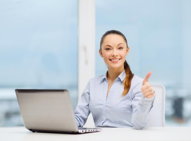 Koncepcja biznesowa i technologiczna - kobieta z laptopem w biurze pokazuje kciuk w górę