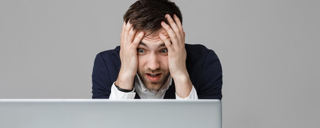 Bezpłatne zdjęcie koncepcja biznesowa portret przystojny stresujący biznesmen w garniturze szok patrząc na pracę w laptopie białe tło