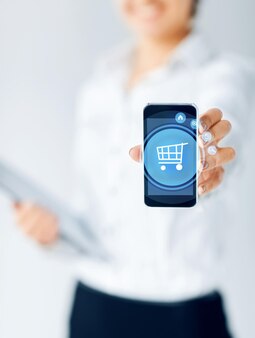 Koncepcja biznesu, ludzi i technologii - zbliżenie bizneswoman pokazujący ekran smartfona z ikoną wózka na zakupy