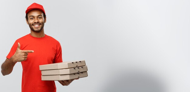 Koncepcja dostawy portret szczęśliwy African American człowiek dostawy wskazując ręką, aby przedstawić pakiety pudełko pizzy izolowany na szarym tle studio Kopia przestrzeń