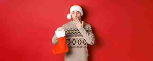 Bezpłatne zdjęcie koncepcja ferii zimowych nowego roku i uroczystości zaskoczyła dorosłego mężczyznę trzymającego skarpetę bożonarodzeniową w...