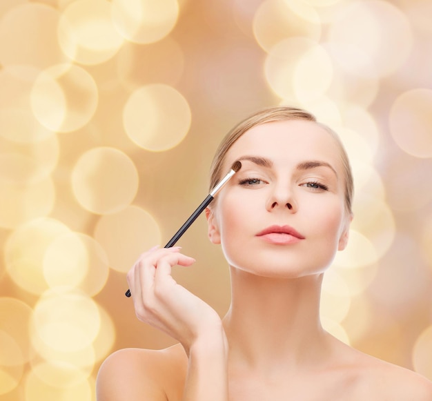 Koncepcja kosmetyków, zdrowia i urody - piękna kobieta z pędzlem do makijażu