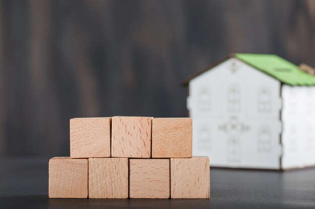 Koncepcja nieruchomości z drewnianymi kostkami, modelem domu i szarością.