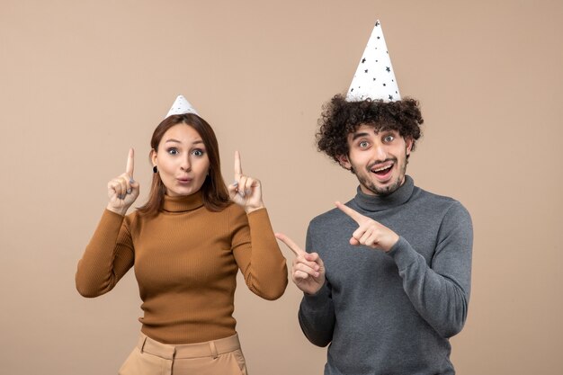 Koncepcja nowego roku z przerażoną młodą parą nosić kapelusz nowego roku dziewczyna i facet na szaro
