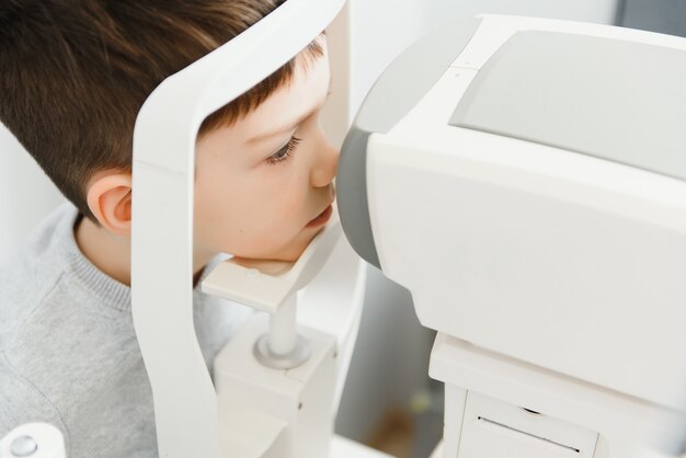 Koncepcja optometrii. kobieta optyk lekarz optyk bada wzrok chłopca w poradni okulistycznej