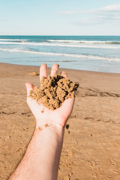 Koncepcja plaży z ręki trzymającej piasek