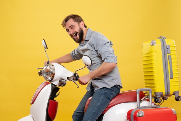 Koncepcja podróży z młody uśmiechnięty szczęśliwy brodaty mężczyzna siedzi na motocyklu na żółtym tle