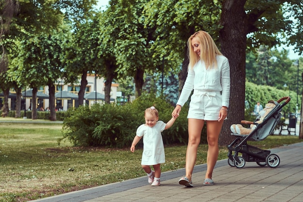 Koncepcja rodziny i ludzi - szczęśliwa blondynka matka z córeczką w parku.