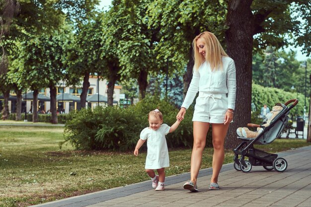 Koncepcja rodziny i ludzi - szczęśliwa blondynka matka z córeczką w parku.